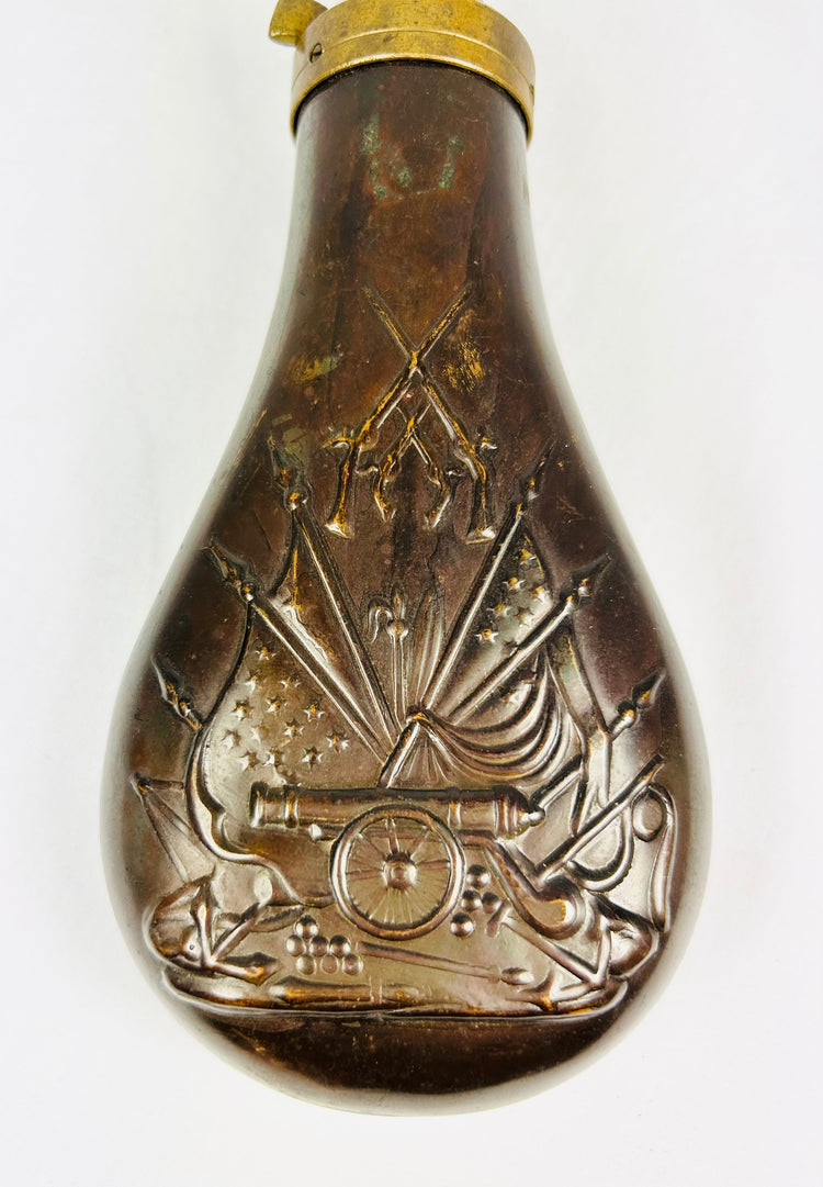 Mid-19th century American copper powder flask with embossed stand of arms motif featuring cannon, U.S. flags, and crossed rifles, brass spout and spring cut-off, Civil War era.