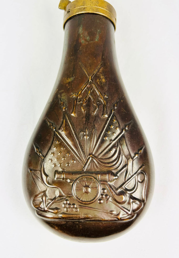 Mid-19th century American copper powder flask with embossed stand of arms motif featuring cannon, U.S. flags, and crossed rifles, brass spout and spring cut-off, Civil War era.