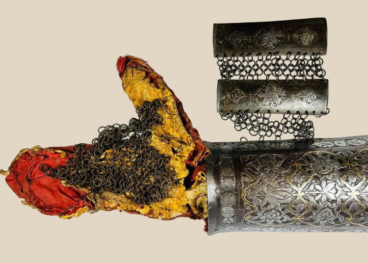 Persian Qajar-era steel bazu band (arm guard), 19th Century CE, featuring intricate gold koftgari inlay, original chain-mail lining, and rare red fabric interior. Designed for forearm protection in battle, combining functionality with luxurious artistry. Reflects Persian metalworking skill, military prestige, and elite craftsmanship of the Qajar dynasty.
