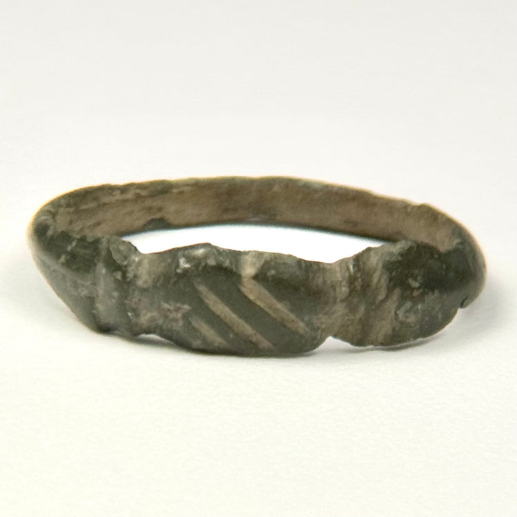 Ancient bronze finger ring with three diagonal engraved lines across the flattened front bezel