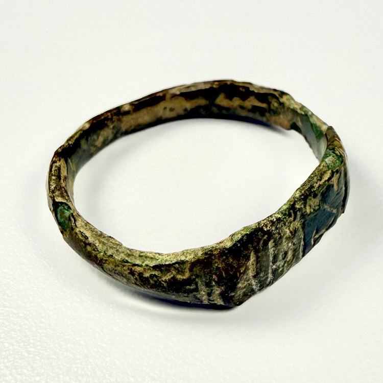 Ancient Roman bronze jewelry with engraved geometric face, angular band, oxidation, and earthen encrustation