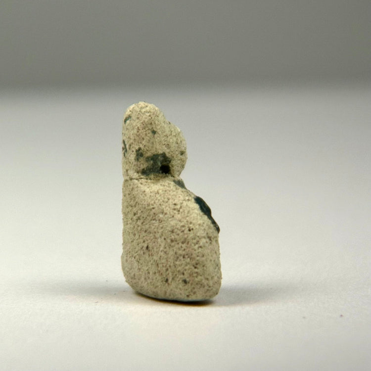 Ancient Egyptian seated cat charm in glazed faience, dating to approximately 600–200 BCE and showing age-related glaze loss.