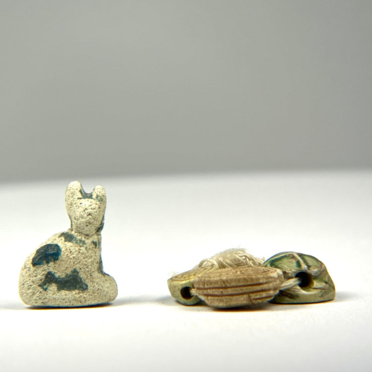 Ancient Egyptian Bastet cat amulet alongside three scarab amulets representing protection, rebirth, and personal devotion, circa 600–200 BCE.