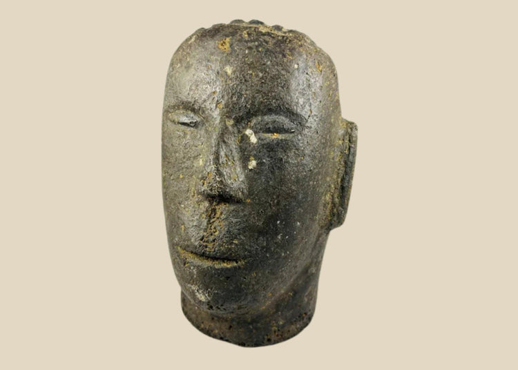 Antique Polynesian volcanic stone head sculpture, carved with stylized facial features and linear hair details, used for ancestor veneration, photographed on a white background.