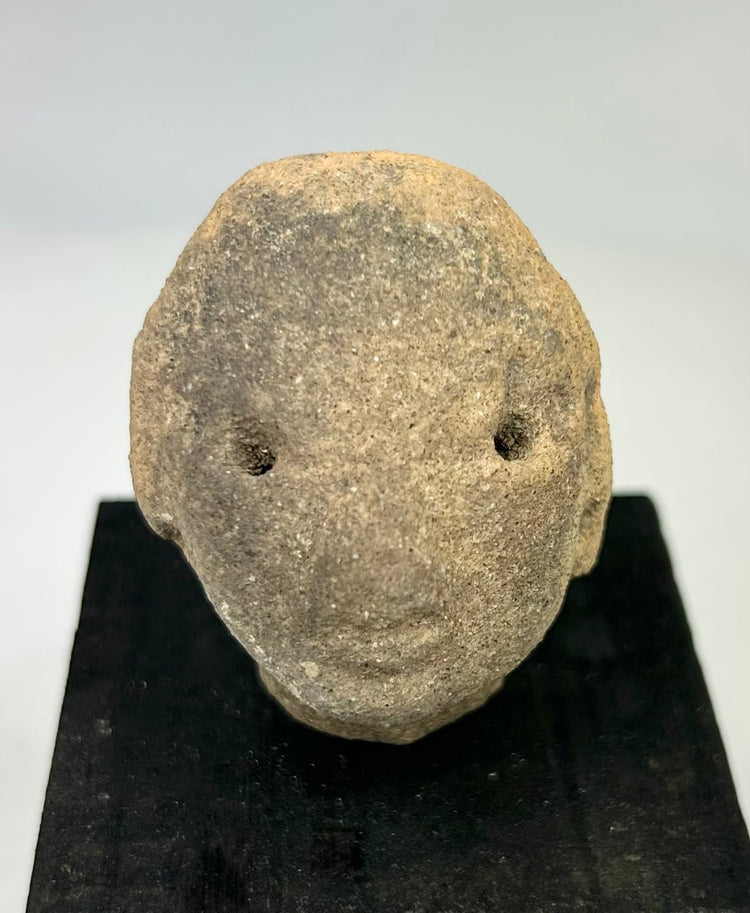 Terracotta head fragment from Nayarit or Jalisco, Pre-Columbian, with subtle mouth and drilled eyes, mounted for display, 300 BCE–300 CE