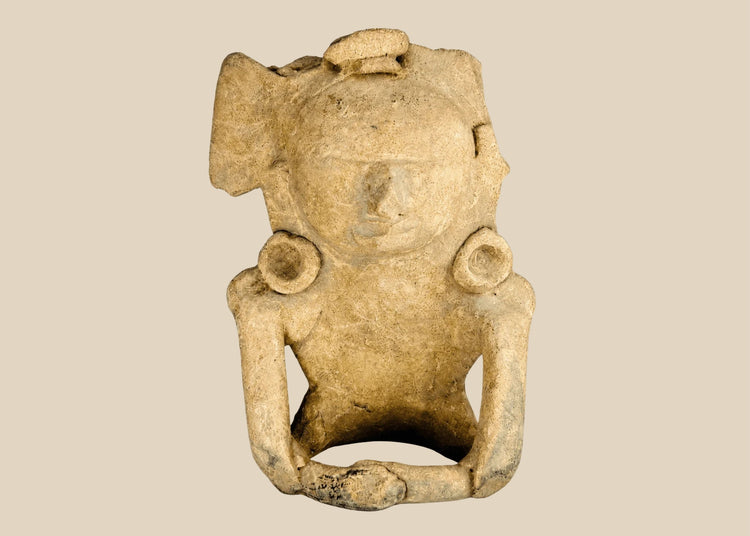 Ancient Mesoamerican terracotta figurine depicting a seated human with helmet-like headpiece, large circular ear ornaments, and hollow cavity in back for ritual use, Classic Period (200–800 AD).