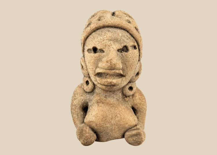 Ancient West Mexican terracotta female figurine, seated with earspools and headdress, hand-modeled with expressive facial features, mounted on a black display base, photographed on a white background.