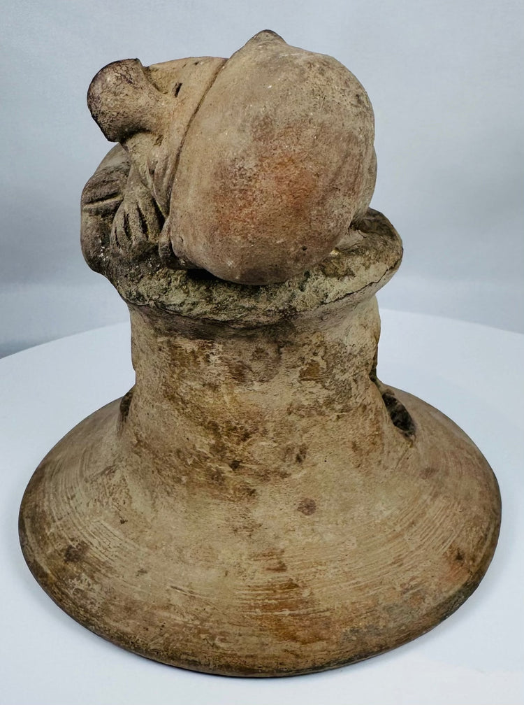 Ancient Ecuadorian ceremonial brazier lid featuring a recumbent figure, large ear ornaments, and vented construction.