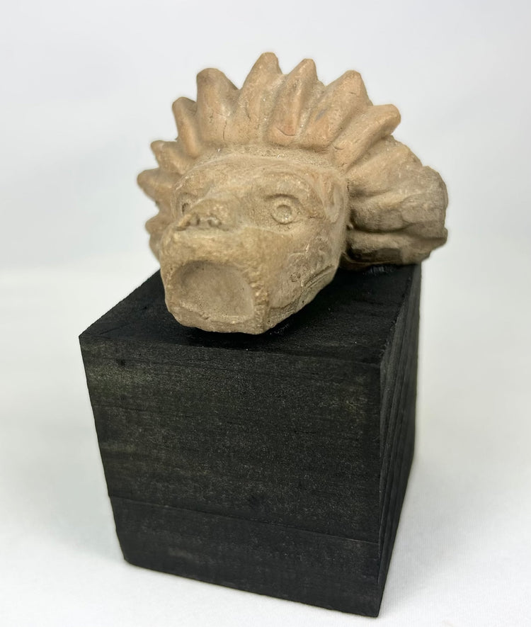Ancient Mesoamerican stone guardian head fragment with open mouth and radiating crest
