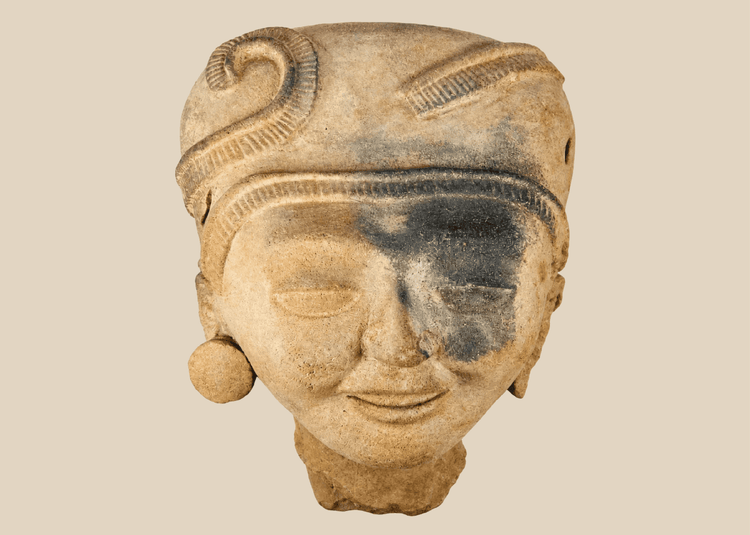 Pre-Columbian terracotta head with intricate hairstyle and large ear ornaments, Mesoamerican origin.