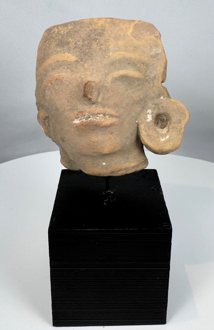 Authentic Pre-Columbian terracotta sculpture fragment from ancient Mesoamerica displayed on a stand.