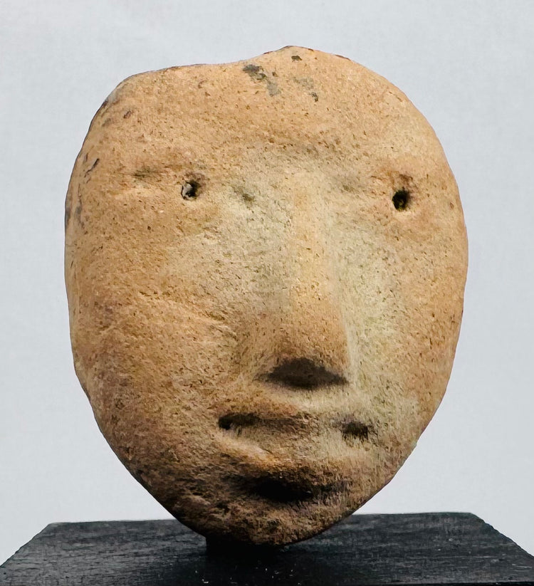 Ancient terracotta effigy head fragment displaying a prominent nose, recessed eyes, and pursed lips.