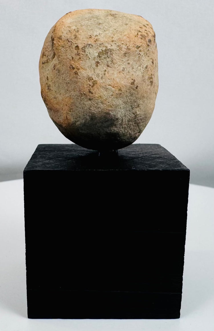 Stylized Pre-Columbian terracotta face fragment mounted for display with visible weathering and age.