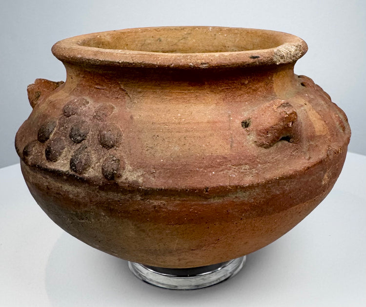 Pre-Columbian ceramic vessel featuring raised decorative elements and a naturally aged red-brown clay surface.