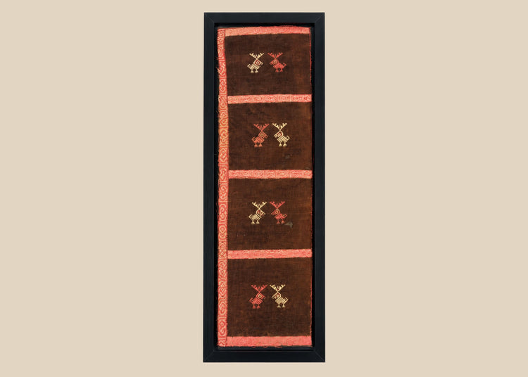 Ancient Pre-Columbian textile fragment featuring geometric animal motifs embroidered in red, gold, and tan thread on a dark brown woven ground, preserved in a protective display frame, dating to circa 1000–1400 CE, representing Andean artistry and symbolic ritual use.
