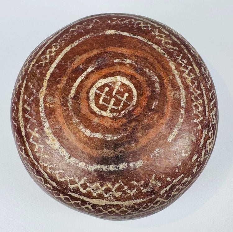 Ceramic bowl underside with concentric rings surrounding a central geometric motif.
