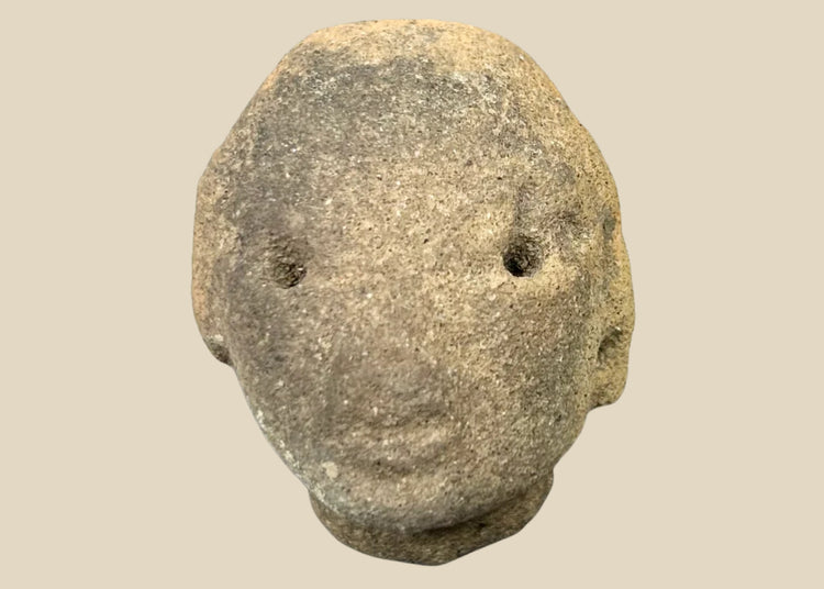 Small Pre-Columbian terracotta head fragment with drilled eyes, rounded features, and subtle mouth, mounted on a black display stand, from West Mexico (Nayarit or Jalisco), circa 300 BCE–300 CE