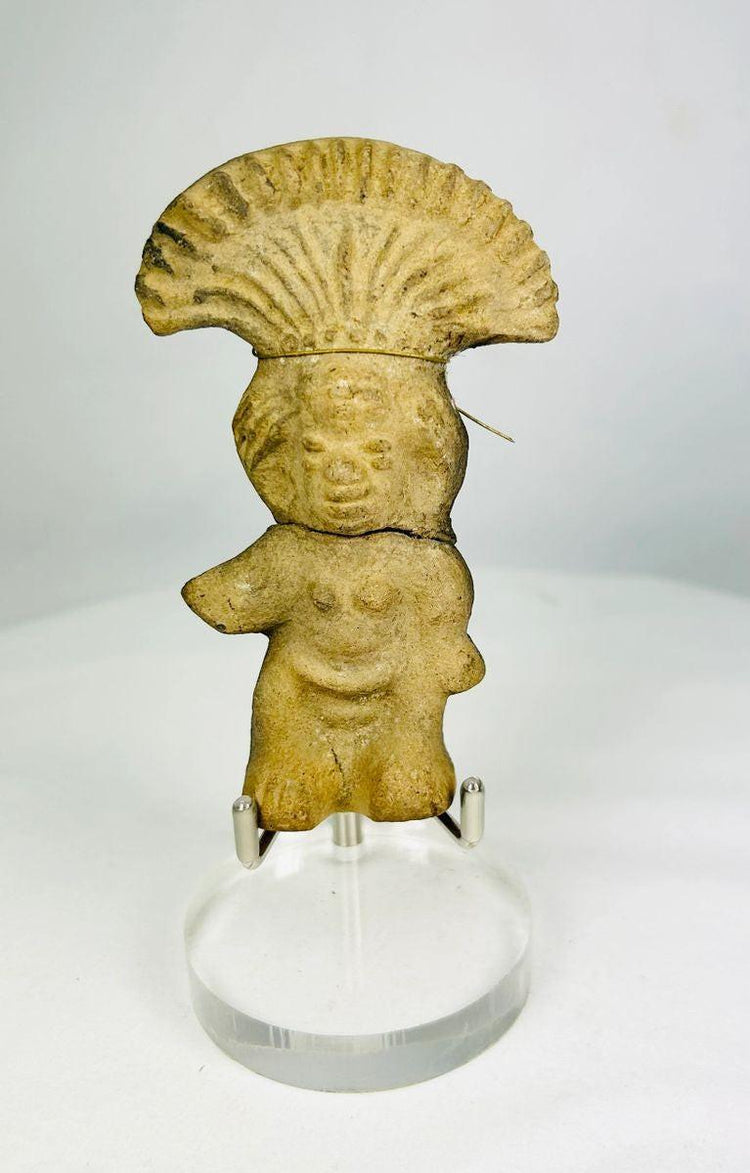 Ancient Pre-Columbian terracotta figurine depicting a standing figure with a wide fan-shaped headdress, stylized facial features, and rounded body, handmade from earthen clay, dating between 500–1500 CE, representing ceremonial or ritual iconography of Mesoamerican cultures.