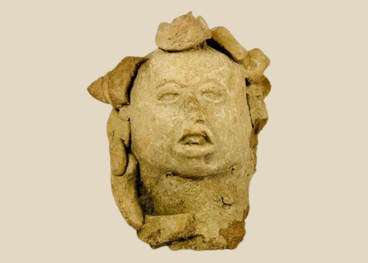 Ancient Pre-Columbian terracotta head from Mesoamerica, featuring stylized facial features with closed eyes, parted lips, and remnants of elaborate headdress elements, hand-molded from clay, dating between 1000–1500 CE, likely used as a ritual offering or funerary effigy.