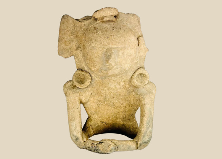Ancient Mesoamerican terracotta figurine depicting a seated human with helmet-like headpiece, large circular ear ornaments, and hollow cavity in back for ritual use, Classic Period (200–800 AD).