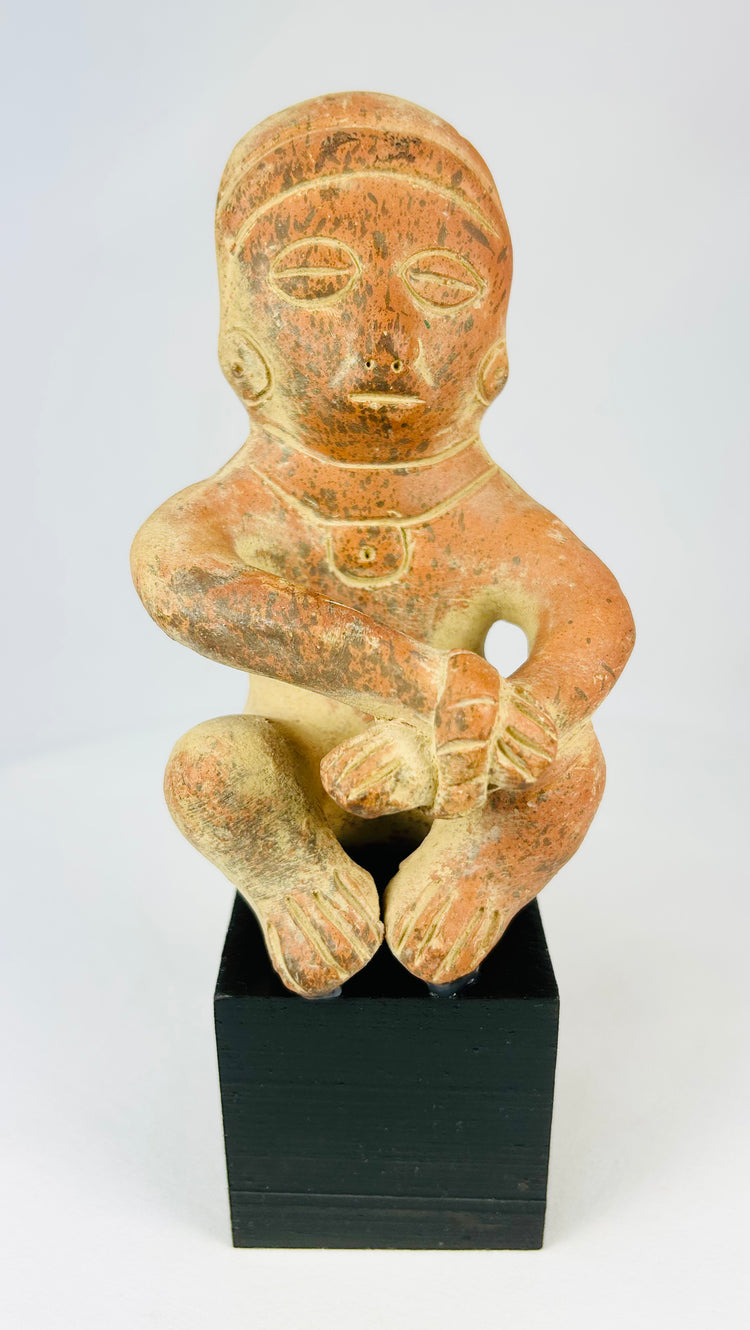 Pre-Columbian seated terracotta figure from West Mexico (Nayarit/Jalisco), circa 300 BCE–300 CE, hand-molded with red slip, stylized anthropomorphic features, burnished surface, shaft tomb funerary artifact on black display stand