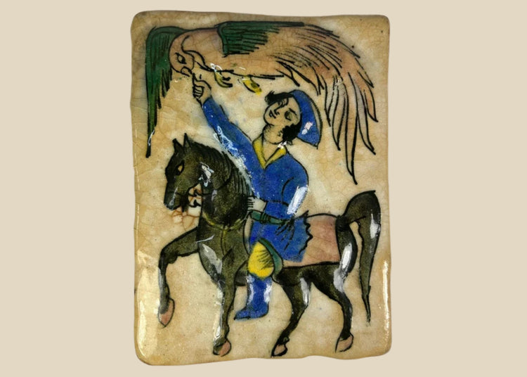 Hand-painted 19th-century Qajar Persian ceramic tile depicting a mounted falconer on horseback in vivid cobalt blue, green, and yellow with crackle glaze.