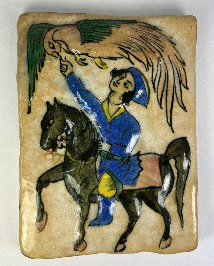 Hand-painted 19th-century Qajar Persian ceramic tile depicting a mounted falconer on horseback in vivid cobalt blue, green, and yellow with crackle glaze.