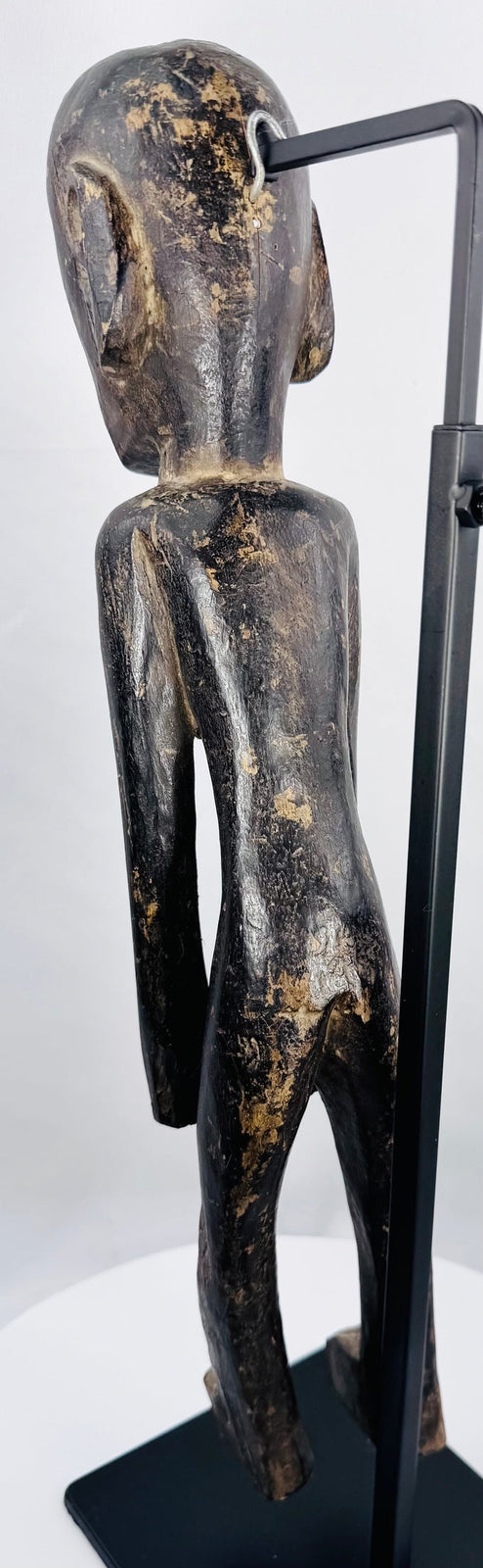Rear view of hand-carved Rapa Nui-inspired moai kavakava figure and aged hardwood surface