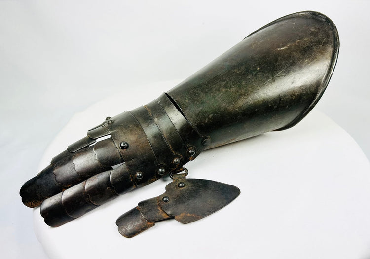 Steel battlefield-style gauntlet with overlapping finger plates and flared cuff, museum-quality photograph.