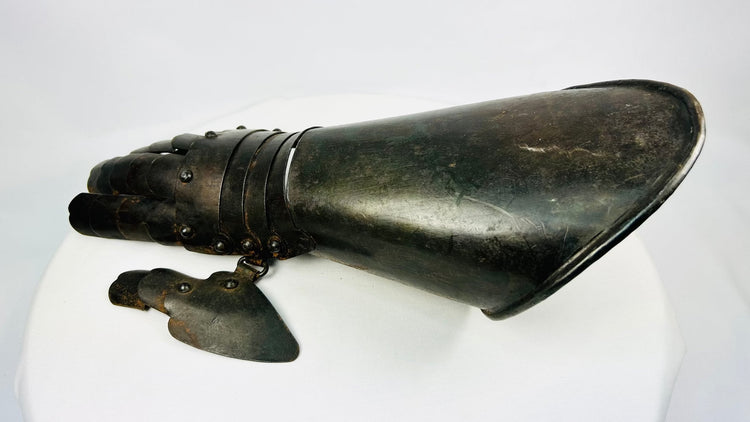 Close-up of 19th-century armour gauntlet reproduction displayed on white studio backdrop.