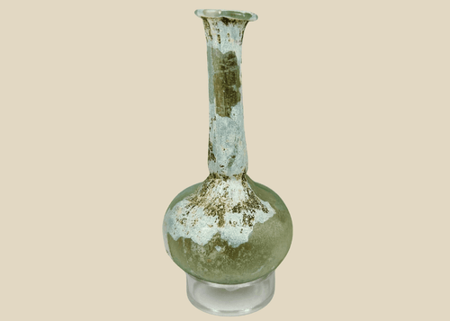 Ancient Roman glass bottle with rounded body and long flared neck, pale green hue and iridescent patina.