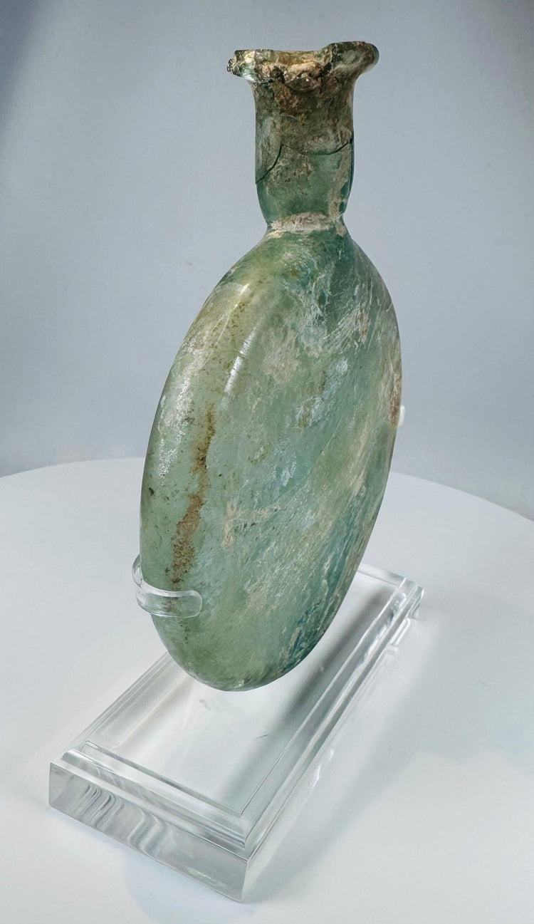 Authentic Roman Empire glass flask featuring flattened circular form and mineral deposits