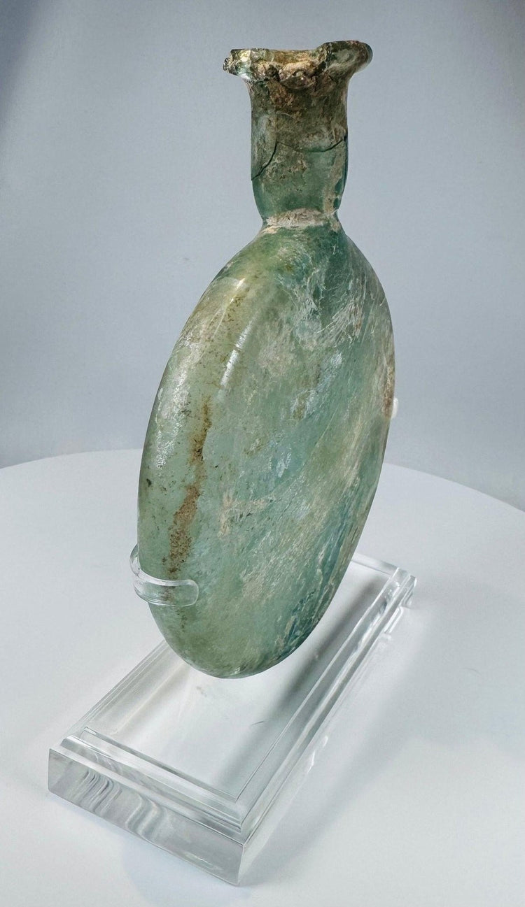 Authentic Roman Empire glass flask featuring flattened circular form and mineral deposits