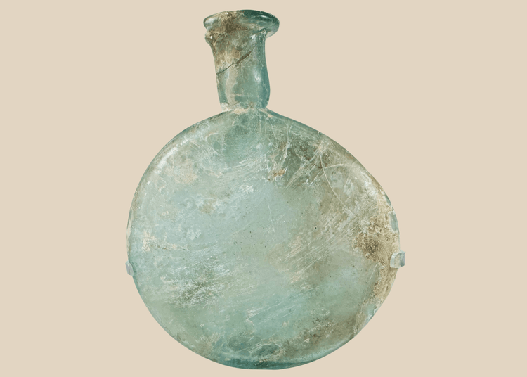 Ancient Roman pale green glass flask with flattened body and long neck displayed on acrylic stand