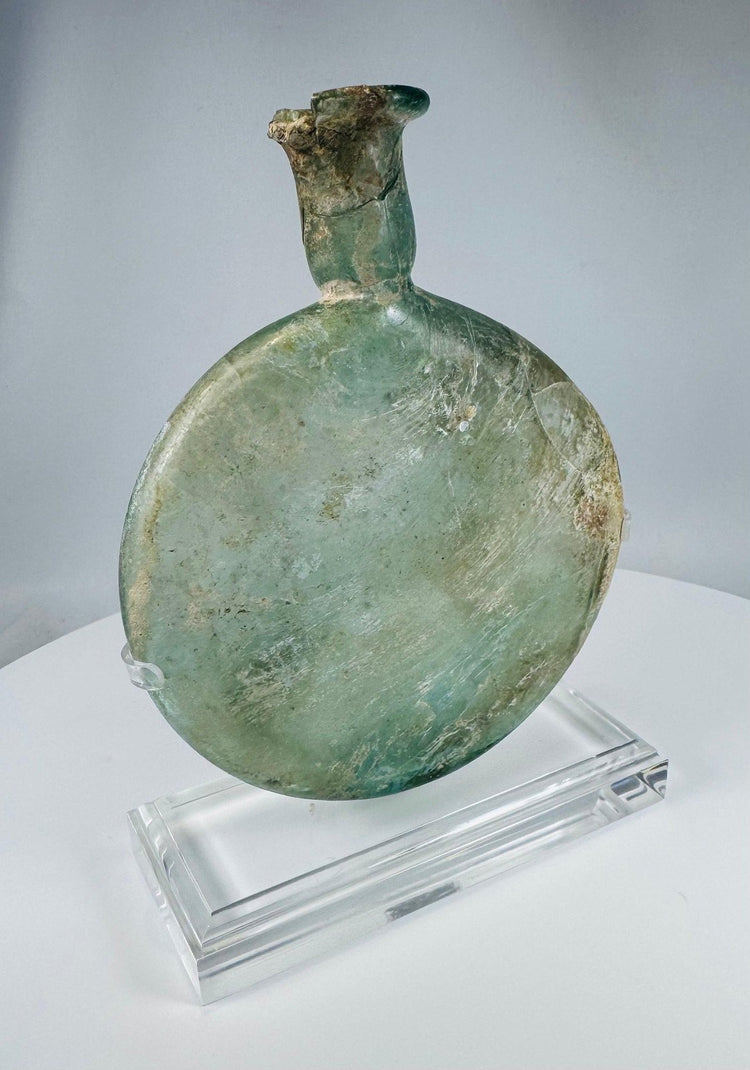 Ancient Roman translucent green glass vessel with weathered surface and elongated neck