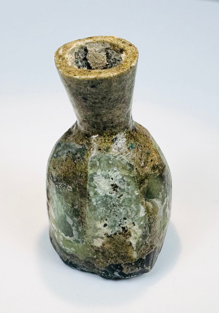 Small ancient glass perfume flask with extensive burial iridescence and encrustation