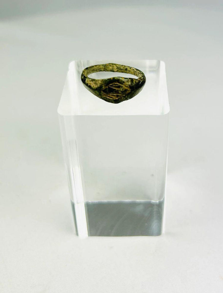 Authentic Roman bronze signet ring, circa 100–300 CE, with oval bezel engraved with geometric intaglio diamond motif, slender tapered band, and rich green patina from centuries of burial, used for sealing documents and personal identity.