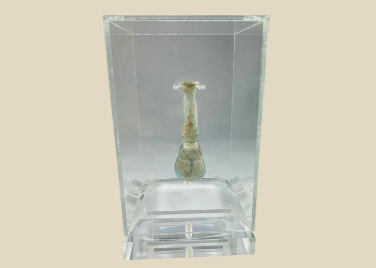 Ancient Roman pale turquoise blown glass balsamarium, 2nd–3rd Century CE. Double-gourd body with tapering neck and outfolded lip, featuring natural iridescent patina. Hand-blown vessel used for perfumes, ointments, and luxury grooming, reflecting Roman craftsmanship, refinement, and elite culture.