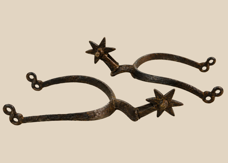 Late 16th–early 17th-century German Saxon spurs forged in iron/steel with large six-pointed rowels, curved frame with high rounded ridge, short hooked shanks with double eye terminals, patinated surfaces, reflecting Renaissance equestrian craftsmanship.