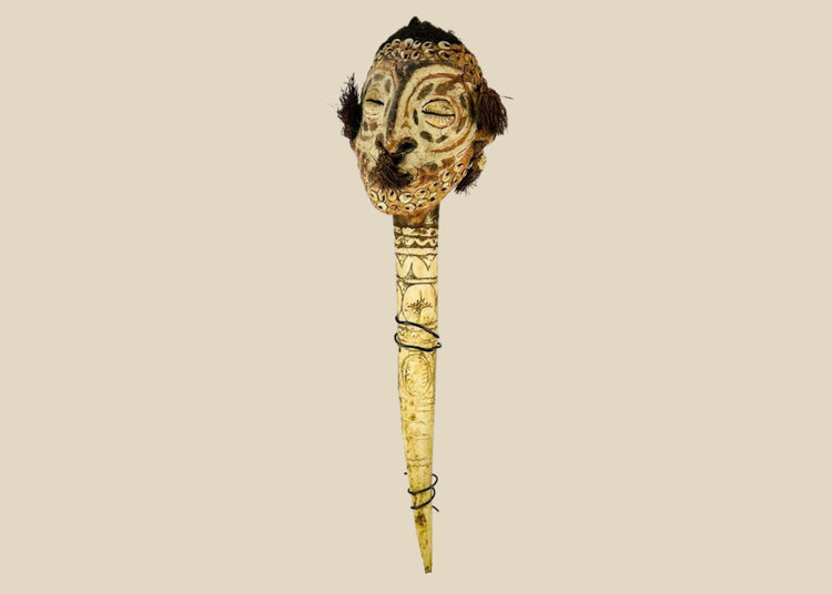 19th-century Sepik River ceremonial bone dagger with carved ancestral head, cowrie shell inlays, human hair adornments, and tribal geometric motifs, used in ritual and initiation rites.