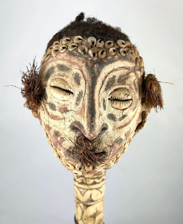 19th-century Sepik River ceremonial bone dagger with carved ancestral head, cowrie shell inlays, human hair adornments, and tribal geometric motifs, used in ritual and initiation rites.
