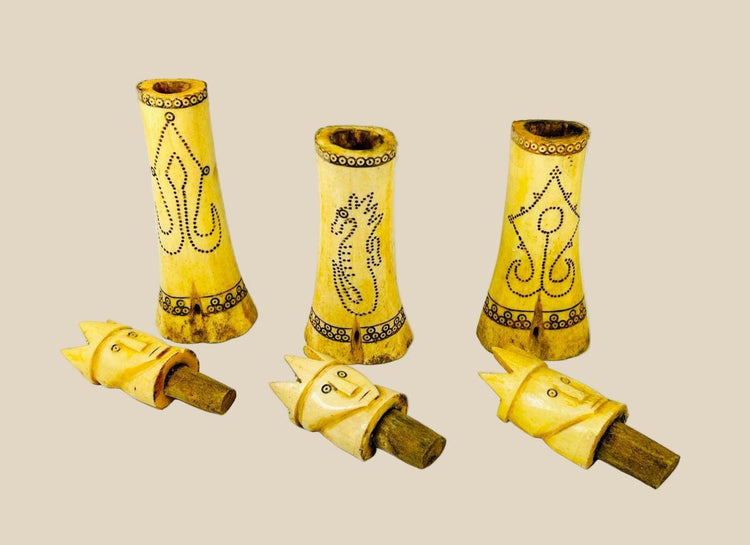 Set of three early 20th-century Indonesian carved buffalo bone lime containers with intricate scrimshaw motifs and lids topped with crowned royal figures, used in traditional betel nut chewing rituals.