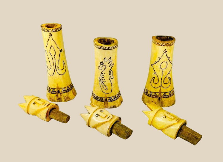 Set of three early 20th-century Indonesian carved buffalo bone lime containers with intricate scrimshaw motifs and lids topped with crowned royal figures, used in traditional betel nut chewing rituals.