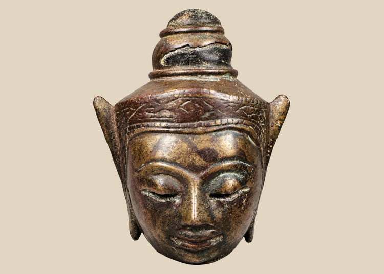 Bronze Buddha head on black display base, featuring serene facial expression, pointed ushnisha, and natural greenish patina, likely from Thailand or Cambodia, 18th–19th century CE.