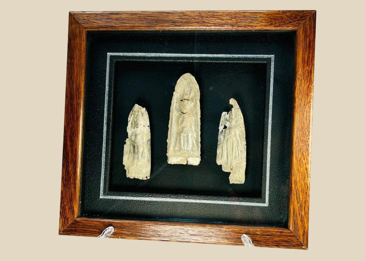 Framed set of three antique cast metal votive plaques from Cambodia or Thailand, 16th–17th Century CE. Central plaque depicts a seated Buddha in meditation, flanked by attendant or deity figures, with intricate engraved details. Mounted on a custom wooden frame, showcasing devotional artistry and Theravāda Buddhist iconography.