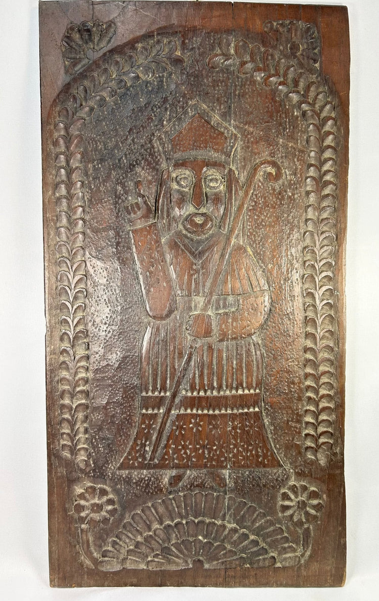 Antique European folk art carving showing bishop saint in relief with palm and laurel motifs