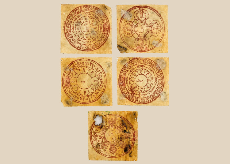 Five circular Tibetan astrological yantras hand-printed in red ink on traditional handmade paper, featuring lotus petals, Eight Auspicious Symbols, and yin-yang motifs, mounted in a modern acrylic display panel, circa 1800s–early 1900s, Tibet/Himalayan Plateau.