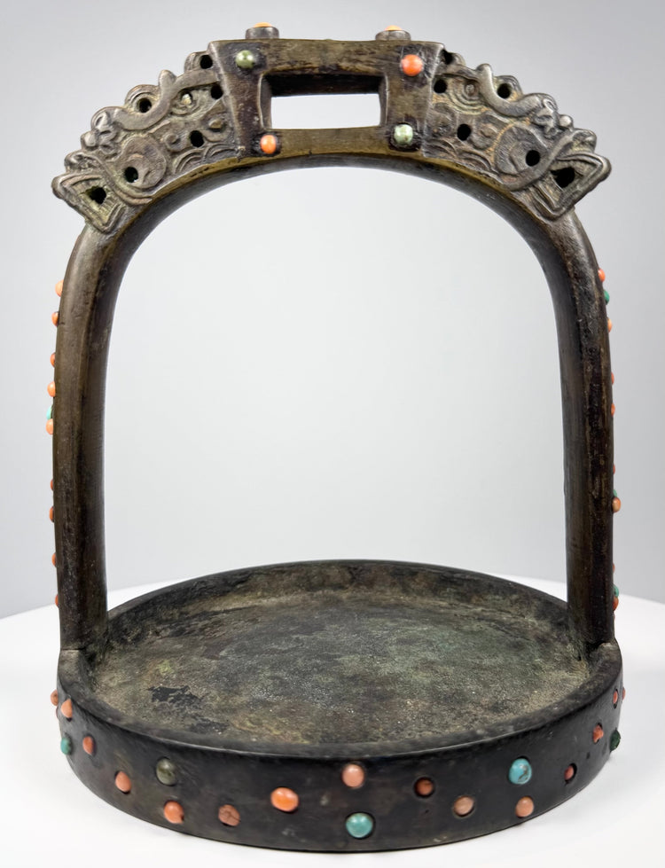 Elite riding stirrup with cast bronze construction, protective dragon motifs, and hand-set coral and turquoise ornament.