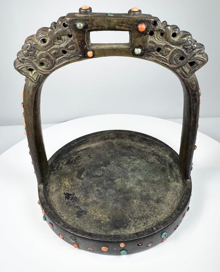 Antique bronze stirrup from the Himalayan region with pierced arch, decorative inlays, and heavy verdigris oxidation.