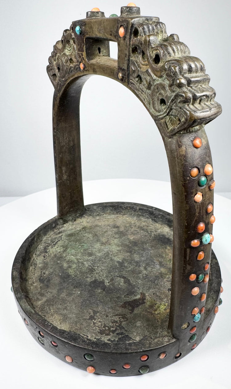 Asian ceremonial horse stirrup with dragon-head terminals, broad footplate, and mixed coral, turquoise, and glass decoration.